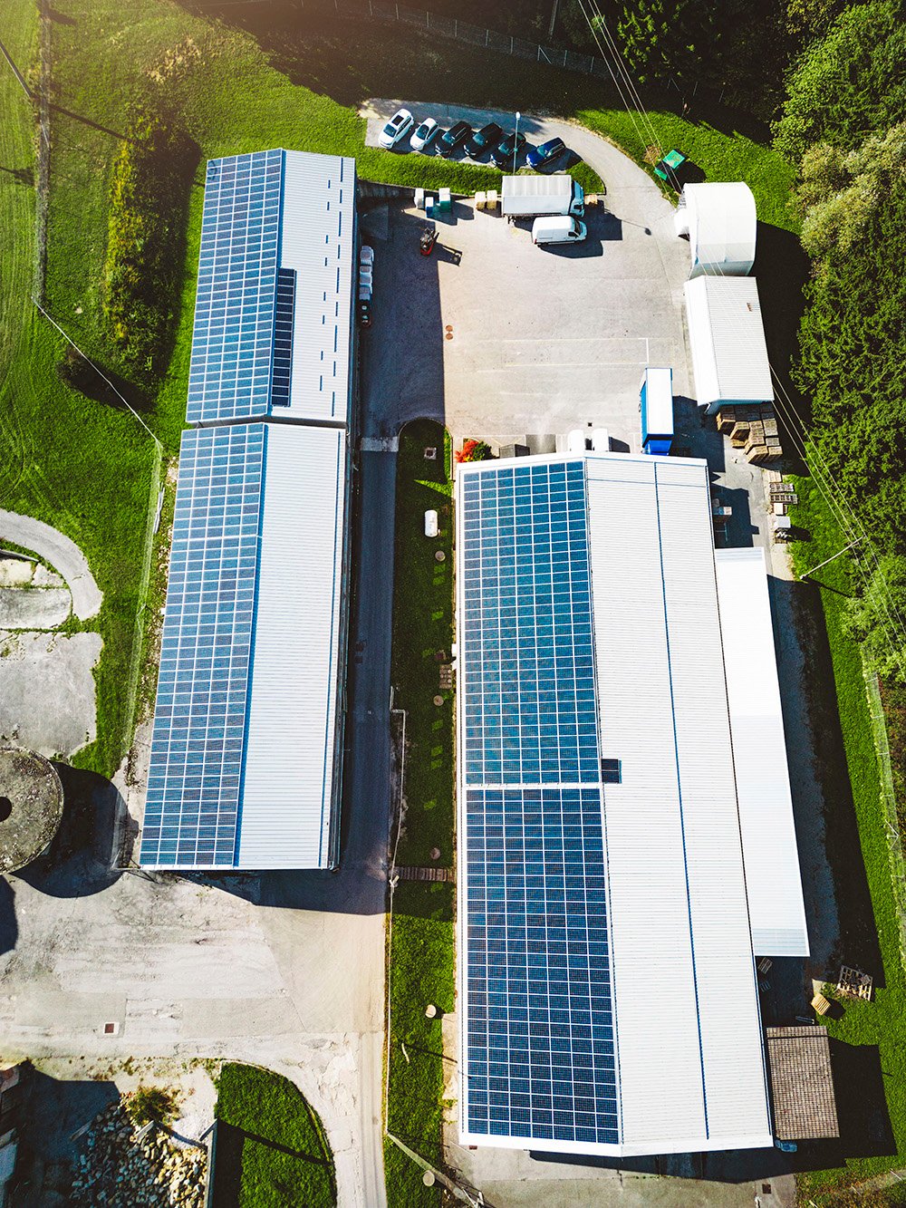 vertical photo top down aerial view solar panels roof two warehouses countryside